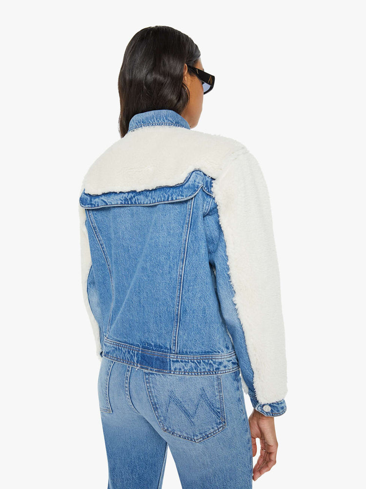 Back view of a mid blue classic denim jacket with faux sherpa with patch pockets and a boxy, slightly cropped fit.