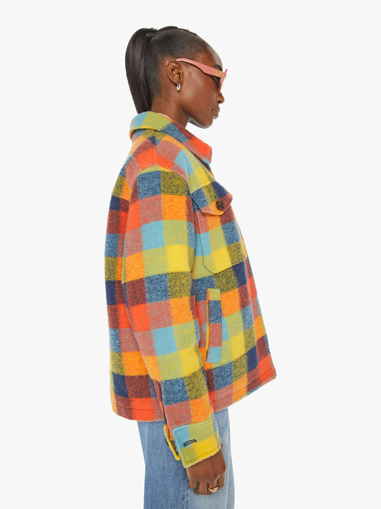 Side view of a woman in a colorful plaid print collared zip-up jacket with oversized patch pockets, drop shoulders and a boxy fit.