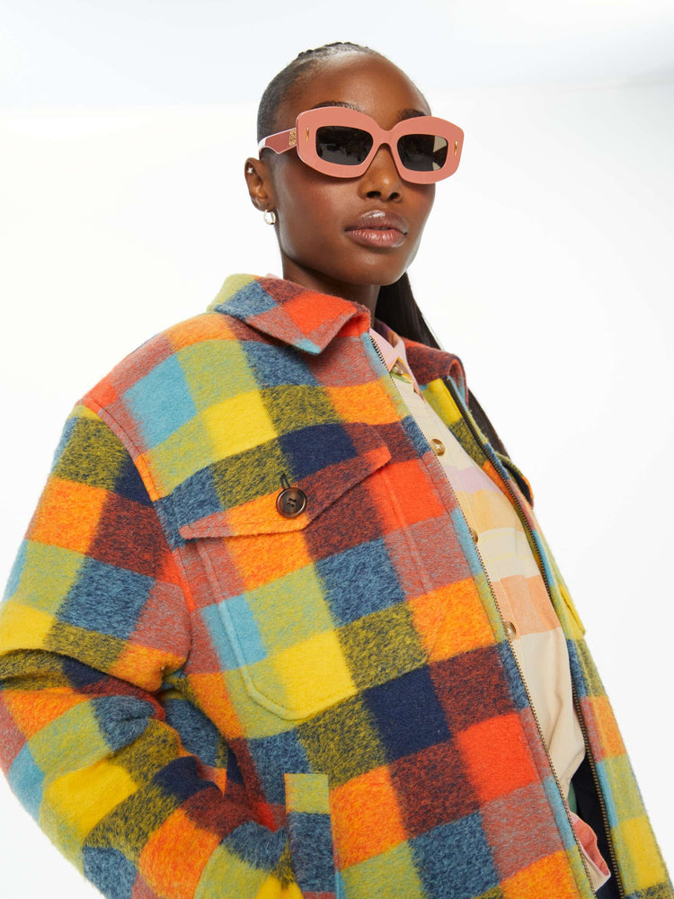 Detailed view of a woman in a colorful plaid print collared zip-up jacket with oversized patch pockets, drop shoulders and a boxy fit.