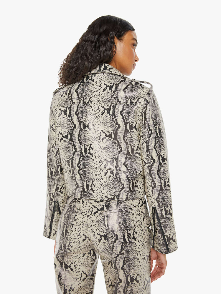 Back view of a woman classic motorcycle jacket with a notched collar, zip pockets, belted waistband and a slightly cropped fit in a cream and black snake print.