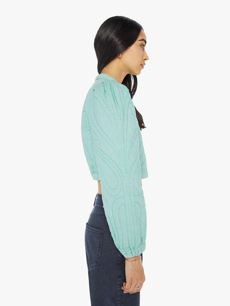 Side view of a woman real cropped crewneck jacket with voluminous balloon sleeves, elastic hems, slit pockets and buttons down the front.