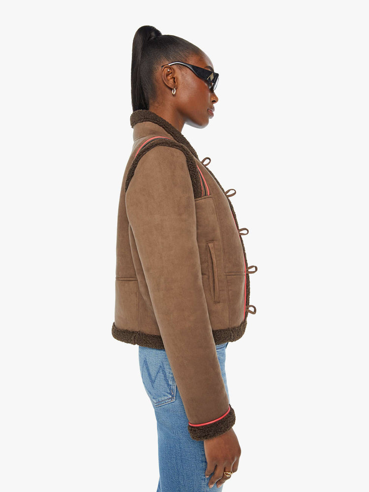 Side view of a woman in a brown faux button-up jacket with red details and faux-shearling trim.