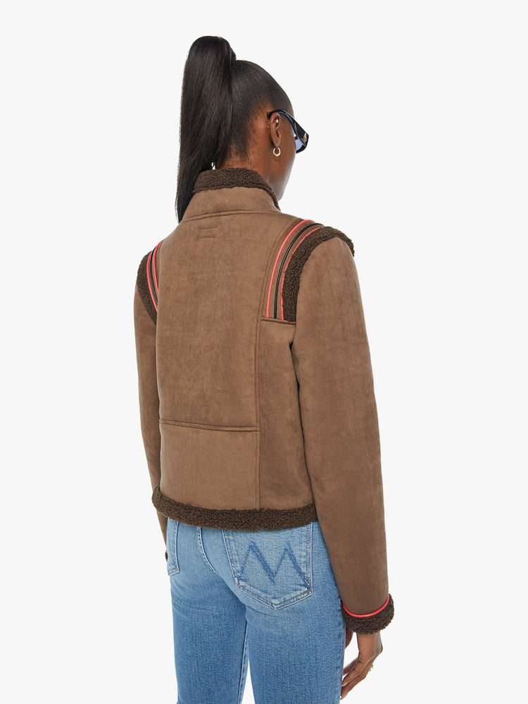 Back view of a woman in a brown faux button-up jacket with red details and faux-shearling trim.