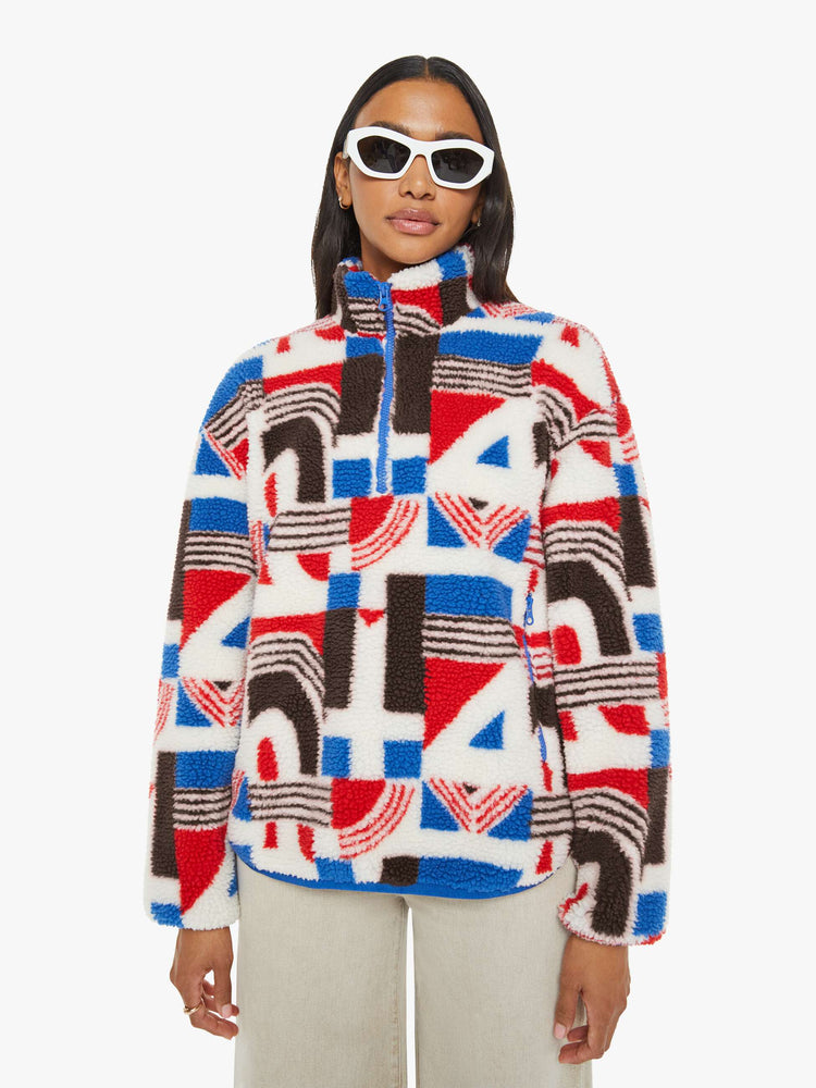 Front view of a woman in a quarter-zip jacket with a stacked collar, drop shoulders, zip pockets and a loose, boxy fit in red, white, blue and brown graphic print.