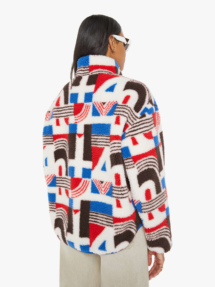 Back view of a woman in a quarter-zip jacket with a stacked collar, drop shoulders, zip pockets and a loose, boxy fit in red, white, blue and brown graphic print.