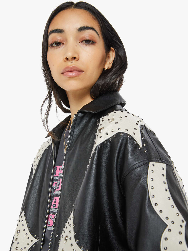 Close up view of a woman in a black with cream patches oversized faux-leather jacket with a collar, drop shoulders, zip closure and snaps at the hem.