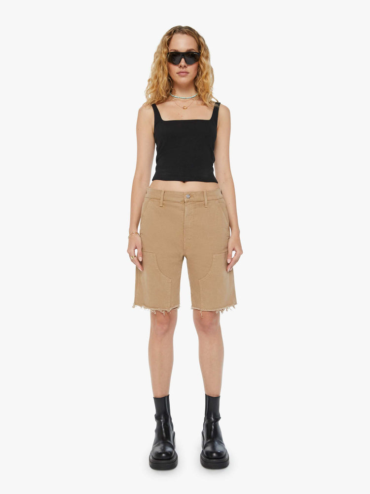 Front view of a woman in dark khaki high-waisted bermuda shorts designed to sit lower on the hips with a long 9.5-inch inseam and a frayed hem.