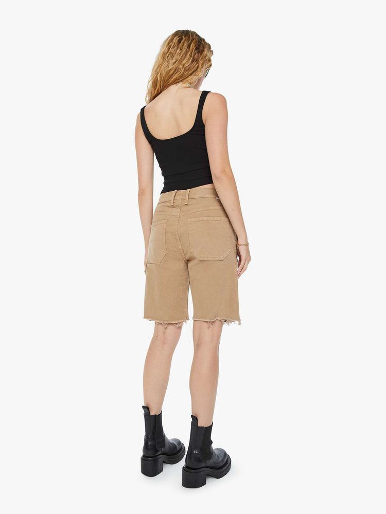 Back view of a woman in dark khaki high-waisted bermuda shorts designed to sit lower on the hips with a long 9.5-inch inseam and a frayed hem.