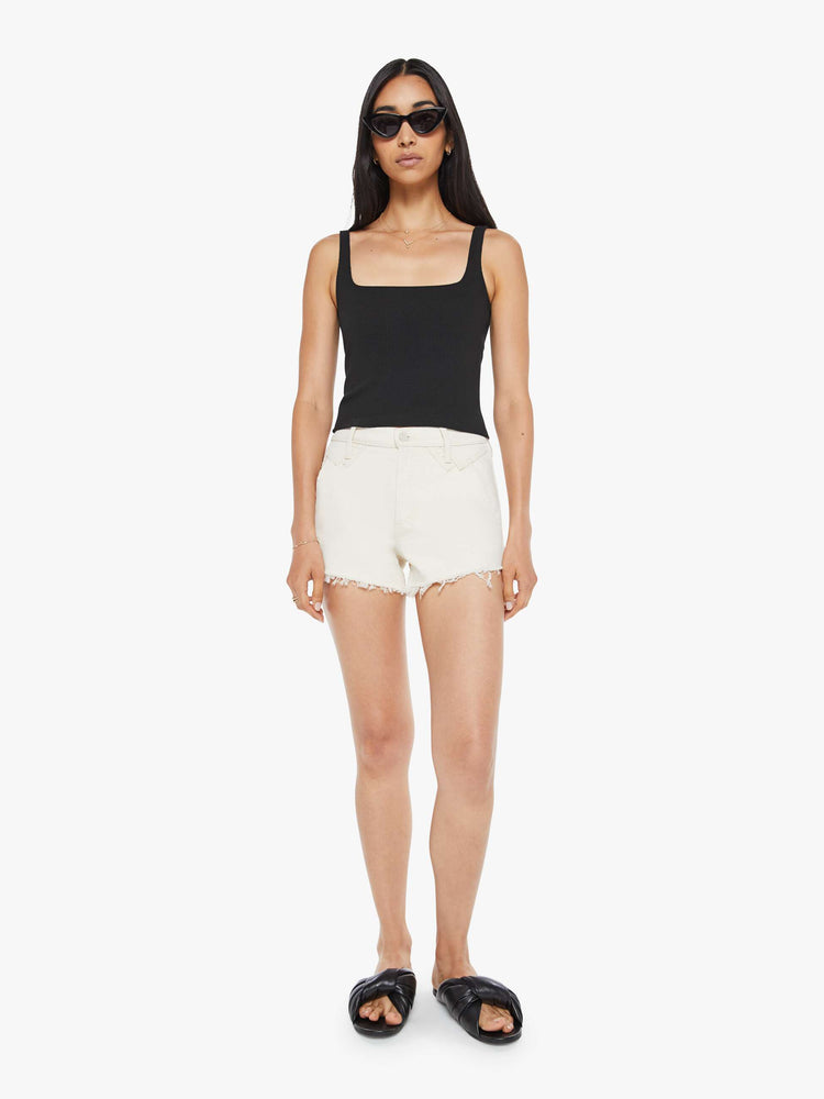 Front view of a woman in high rise jean short with a button fly and frayed hem in creamy white.