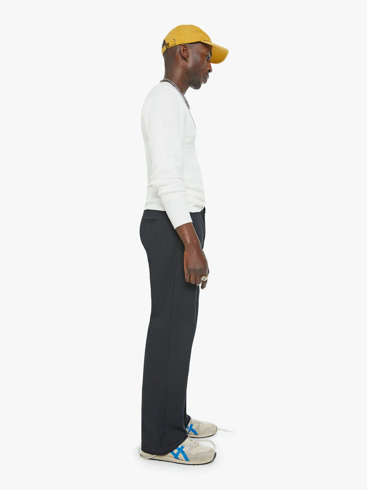 Side view of a man in a black pants with a mid rise, slit pockets and a 31-inch inseam with a clean hem.