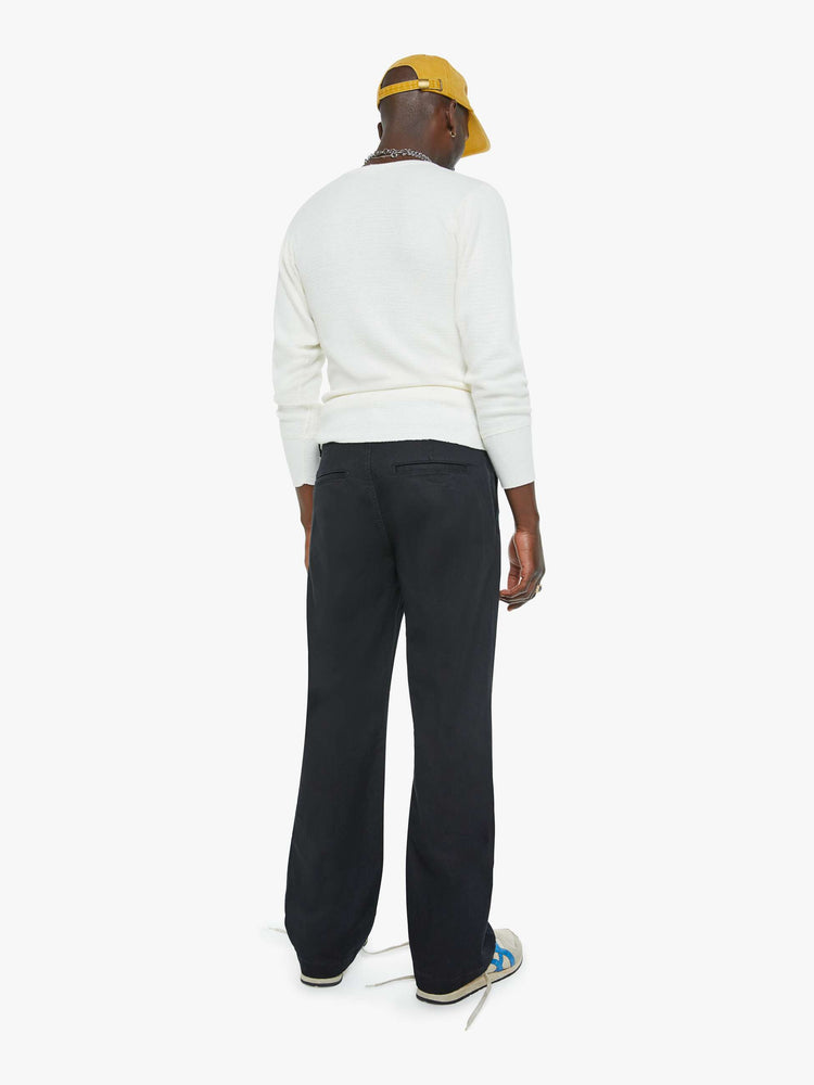 Back view of a man in a black pants with a mid rise, slit pockets and a 31-inch inseam with a clean hem.