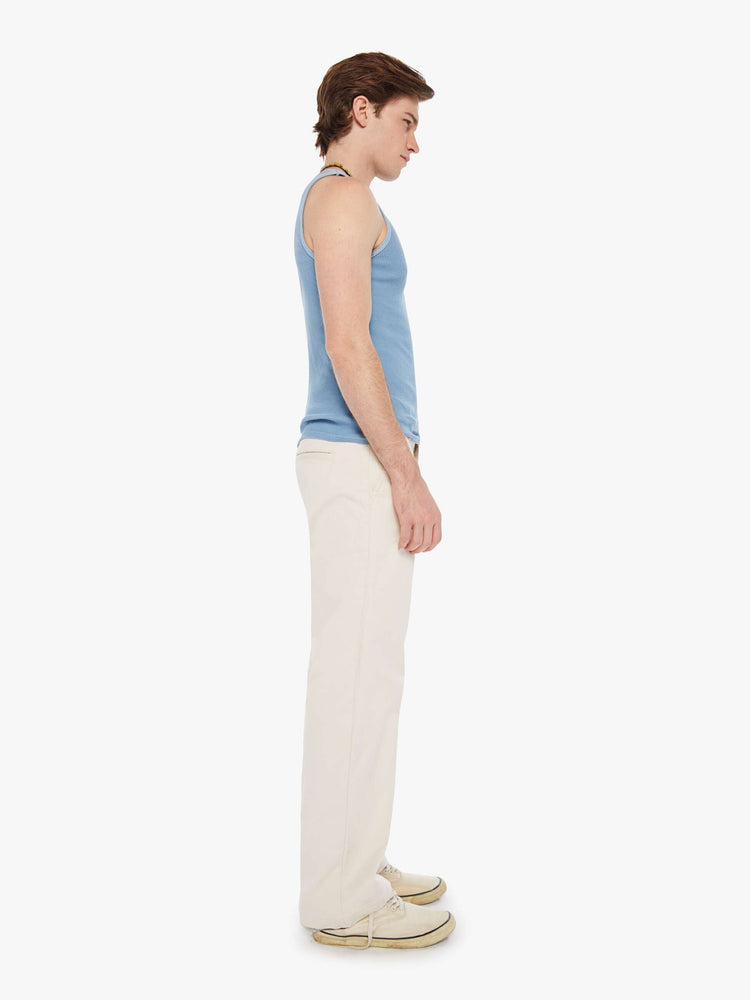 Side view of a man in an off white pants with a mid rise, slit pockets and a 31-inch inseam with a clean hem.