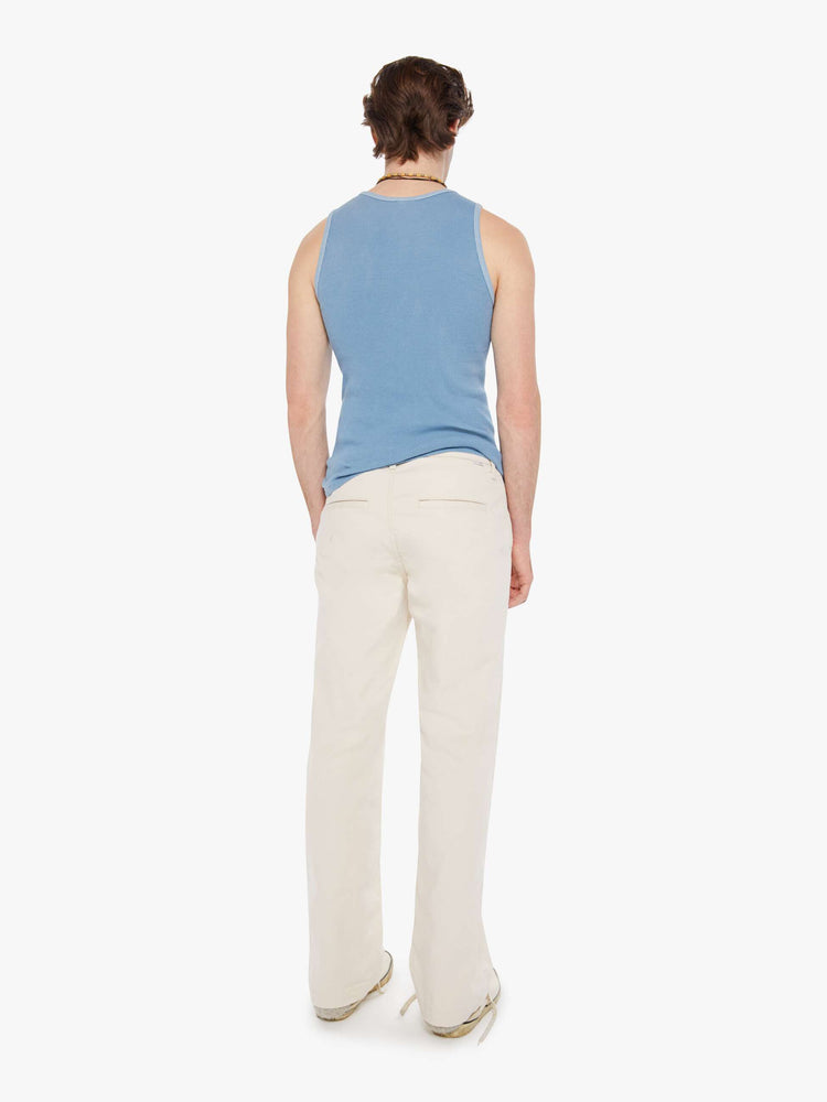 Back view of a man in an off white pants with a mid rise, slit pockets and a 31-inch inseam with a clean hem.
