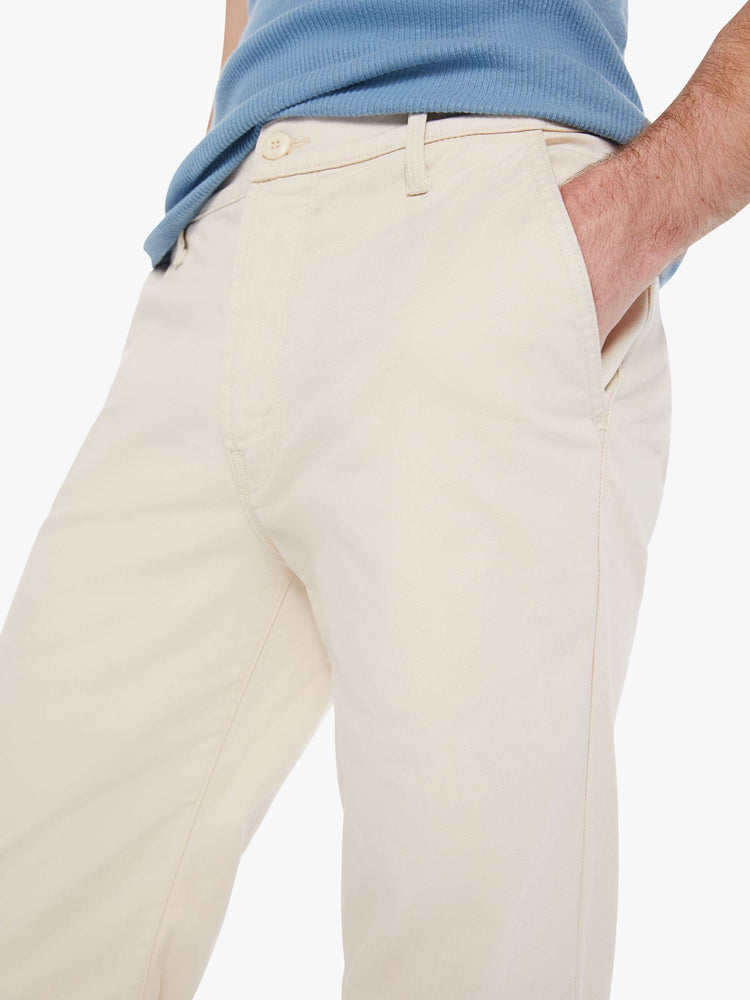 Close up view of a man in an off white pants with a mid rise, slit pockets and a 31-inch inseam with a clean hem.