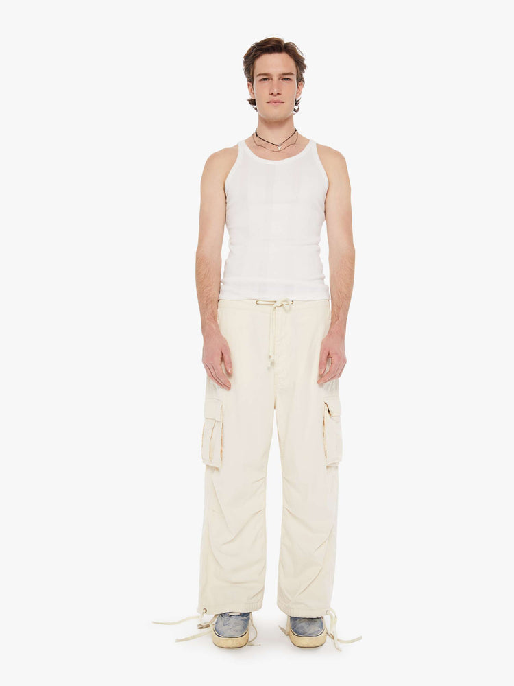 Front view of a men in a creamy white drawstring cargo pants with a loose wide-leg, patch pockets, a 26.5-inch inseam and ties at the hems.