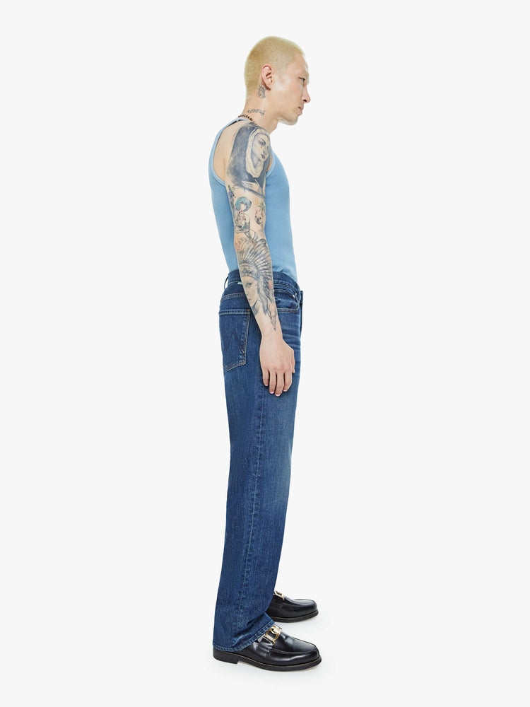 Side view of a man in a mid-rise bootcut with a 31-inch inseam and a clean hem in a dark blue wash.