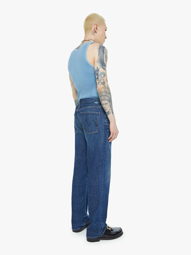 Back view of a man in a mid-rise bootcut with a 31-inch inseam and a clean hem in a dark blue wash.