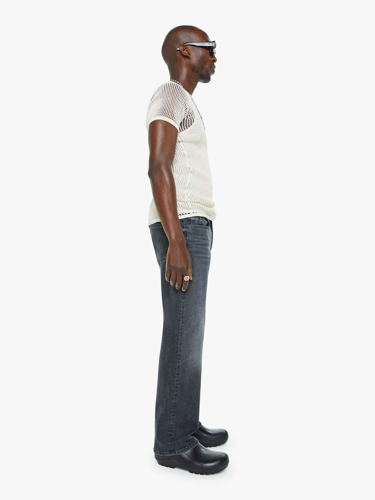 Side view of a man in a mid-rise bootcut with a 31-inch inseam and a clean hem in a faded black wash.