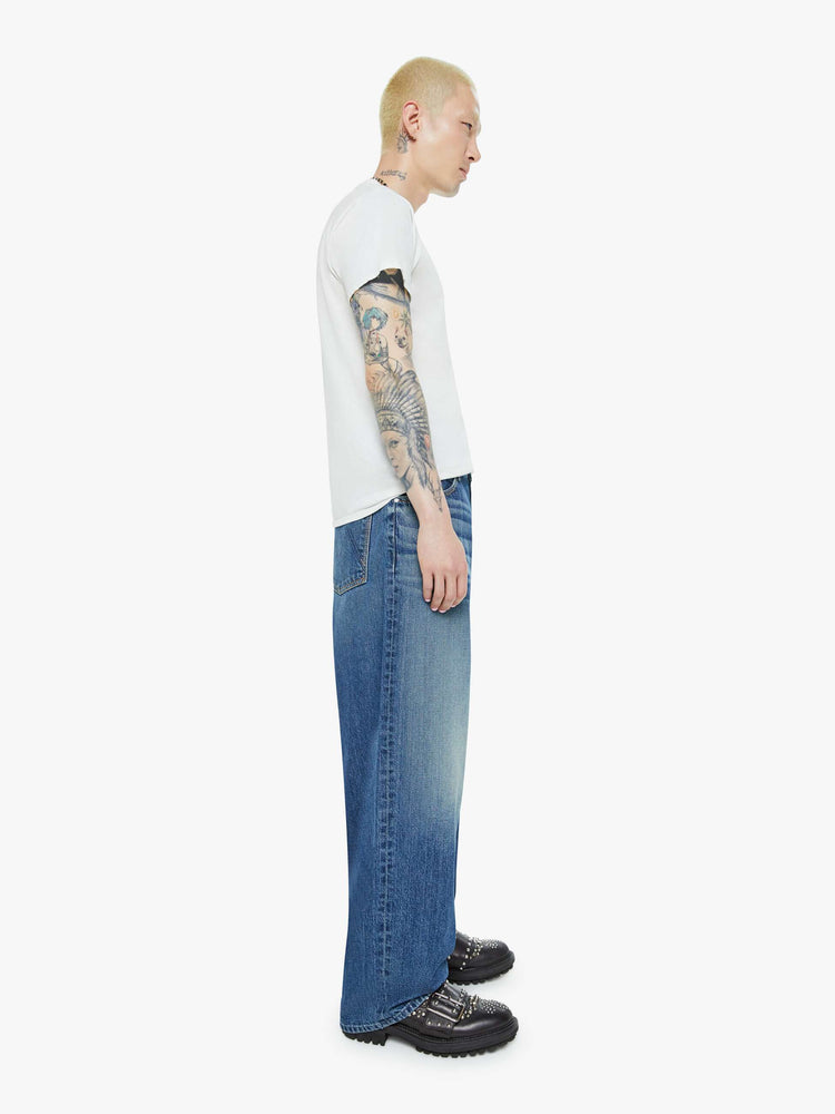 Side view of a men wide straight-leg jean with a high rise, 30-inch inseam, loose fit and a clean hem in mid blue wash.