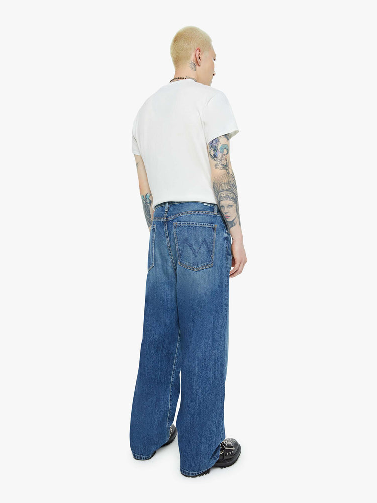 Back view of a men wide straight-leg jean with a high rise, 30-inch inseam, loose fit and a clean hem in mid blue wash.