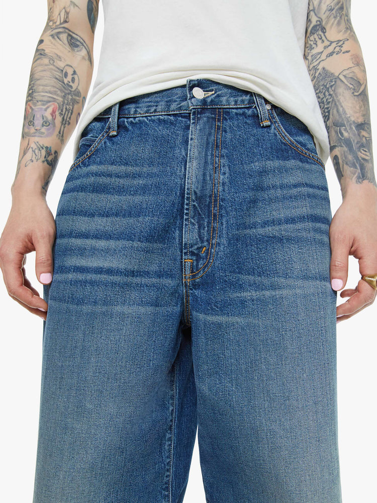 Close up view of a men wide straight-leg jean with a high rise, 30-inch inseam, loose fit and a clean hem in mid blue wash.