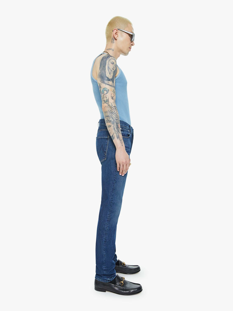 Side view of a man in a slim-straight leg with a mid rise, 32-inch inseam and a clean hem in a dark blue wash.