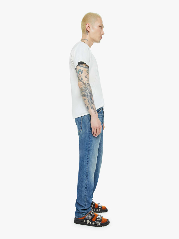 Side view of a man in a slim-straight leg with a mid rise, 32-inch inseam and a clean hem in a mid blue wash.