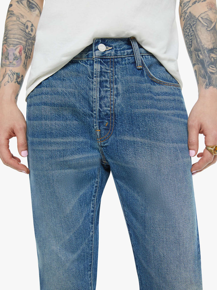 Close up waist view of a man in a slim-straight leg with a mid rise, 32-inch inseam and a clean hem in a mid blue wash.