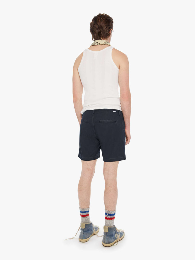 Back view of a man in a navy blue shorts with a mid rise, slit pockets and a 6-inch inseam with a clean hem.