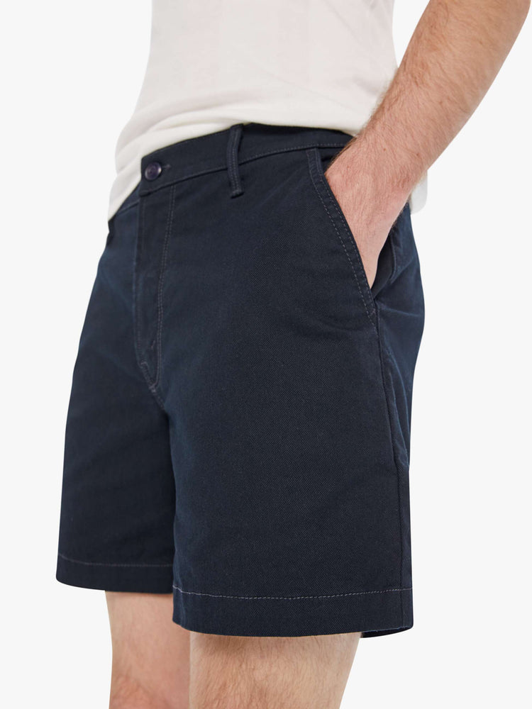 Close up view of a man in a navy blue shorts with a mid rise, slit pockets and a 6-inch inseam with a clean hem.