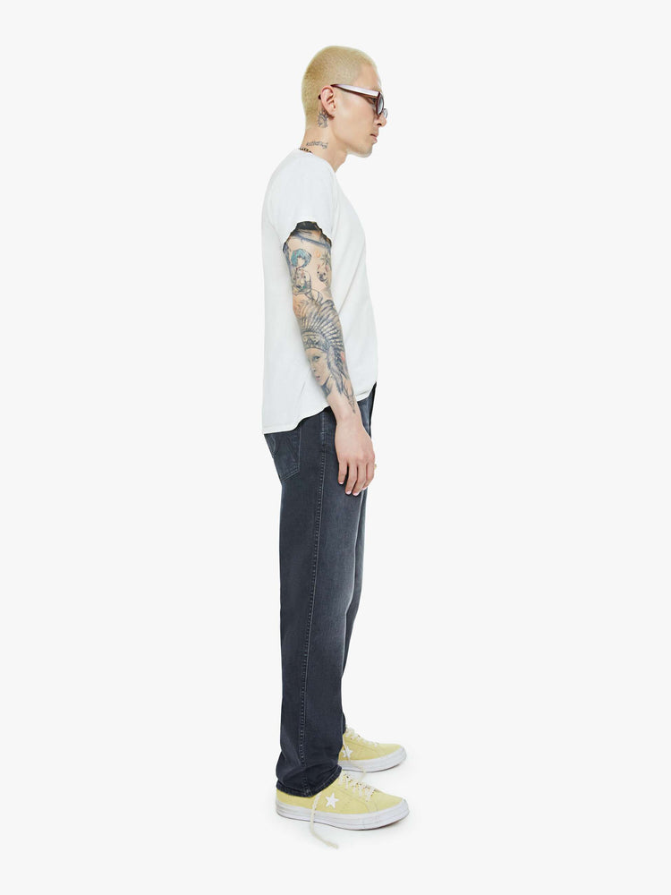 Side view of a man in a dark grey straight-leg jean with a mid rise, zipper fly, 30-inch inseam and a clean hem.