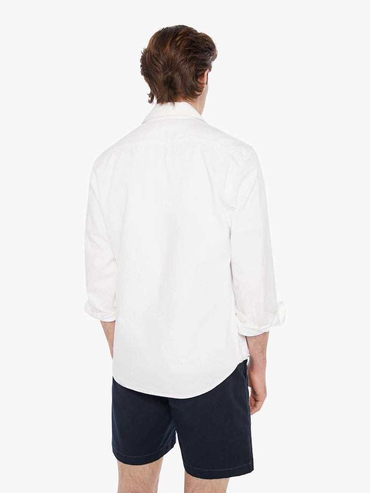 Back view a man in a white collared button-up with a patch pocket and a slightly curved hem.