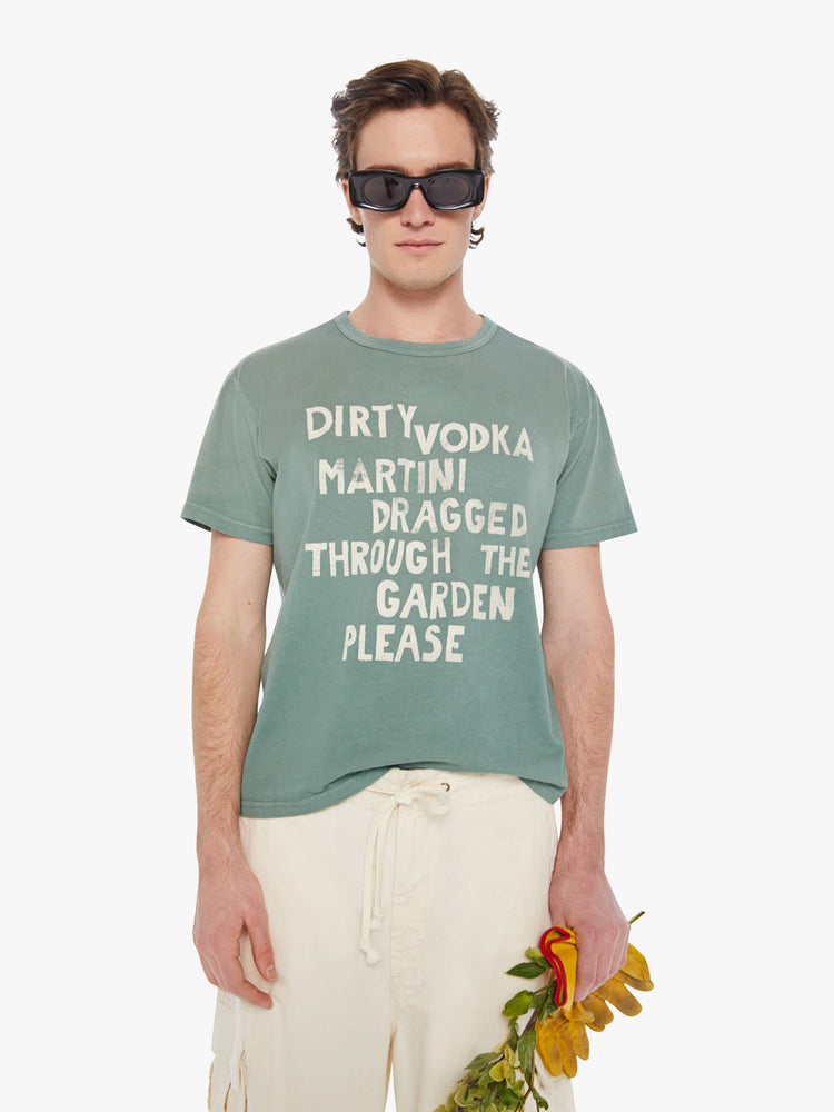 Front view of a man in a pale green oversized tee with drop shoulders and a loose fit featuring an off-white faded text graphic.