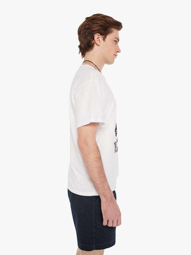 Side view of a man in a white oversized tee with drop shoulders and a loose fit featuring a faded black text graphic. 