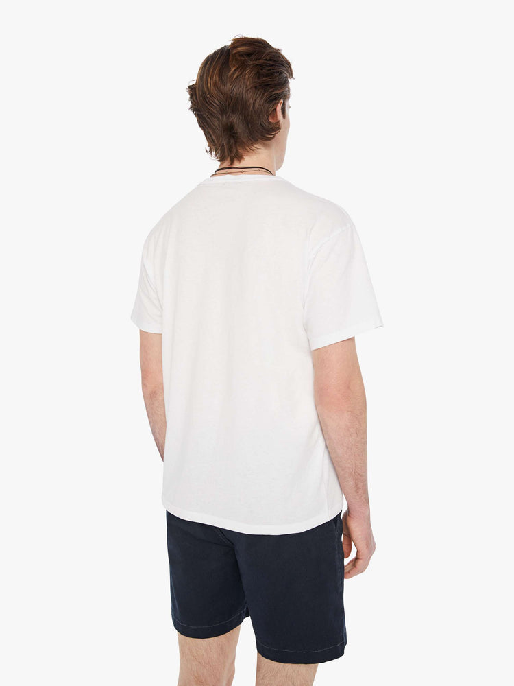Back view of a man in a white oversized tee with drop shoulders and a loose fit featuring a faded black text graphic. 