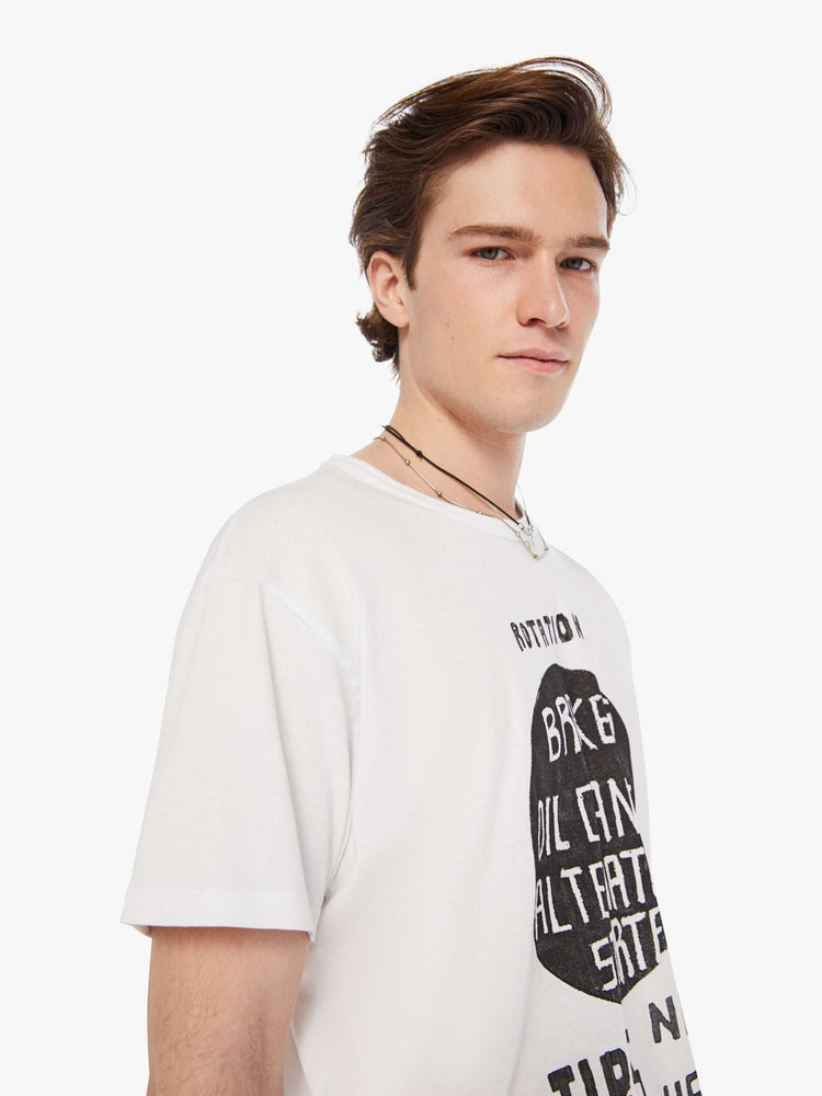 Detailed view of a man in a white oversized tee with drop shoulders and a loose fit featuring a faded black text graphic. 