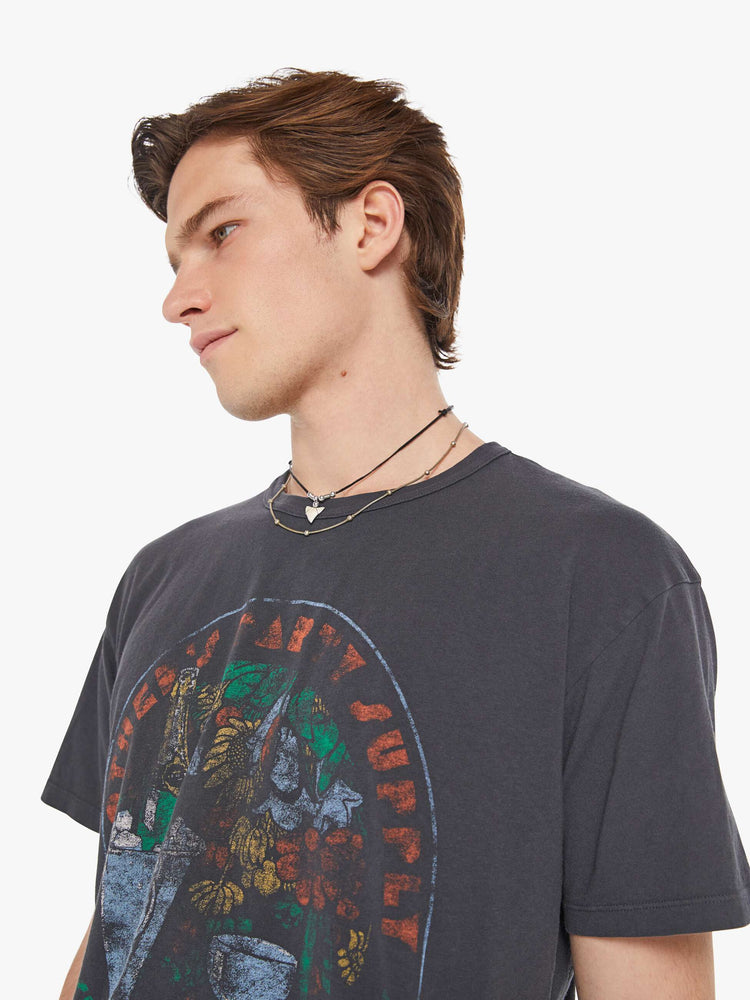 Detailed view of a man in a faded black oversized tee with drop shoulders and a loose fit featuring a vintage inspired faded graphic.