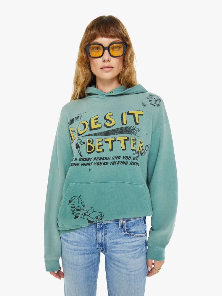 WOMEN front view of an teal oversized hoodie with drop shoulders, ribbed hems and a front patch pocket and colorful text, doodles, and fading at the shoulders.