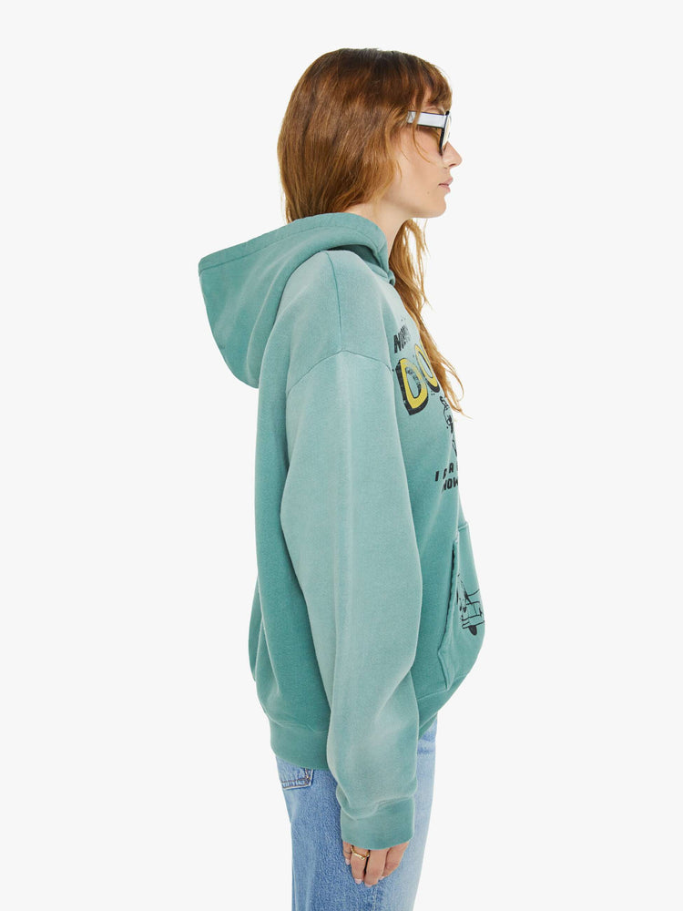 WOMEN side view of an teal oversized hoodie with drop shoulders, ribbed hems and a front patch pocket and colorful text, doodles, and fading at the shoulders.