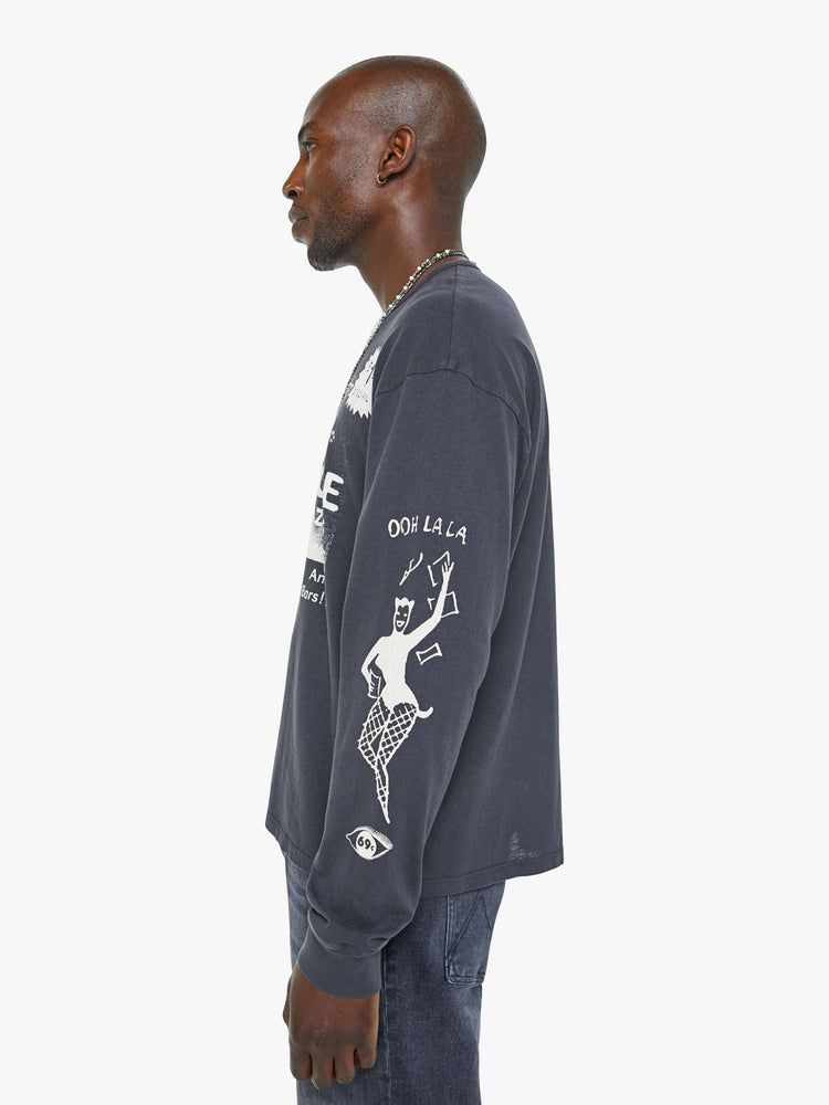 Side view of a man oversized long sleeve tee with drop shoulders and a loose fit in a faded black with an advertisement in white on the front.