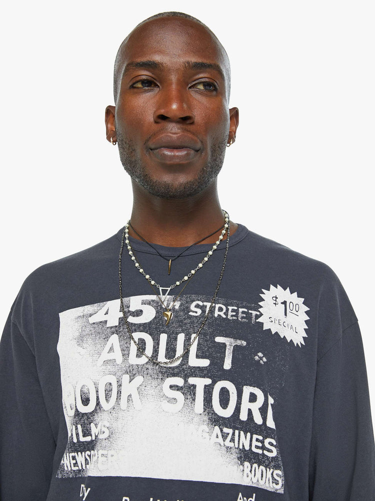 Close up view of a man oversized long sleeve tee with drop shoulders and a loose fit in a faded black with an advertisement in white on the front.