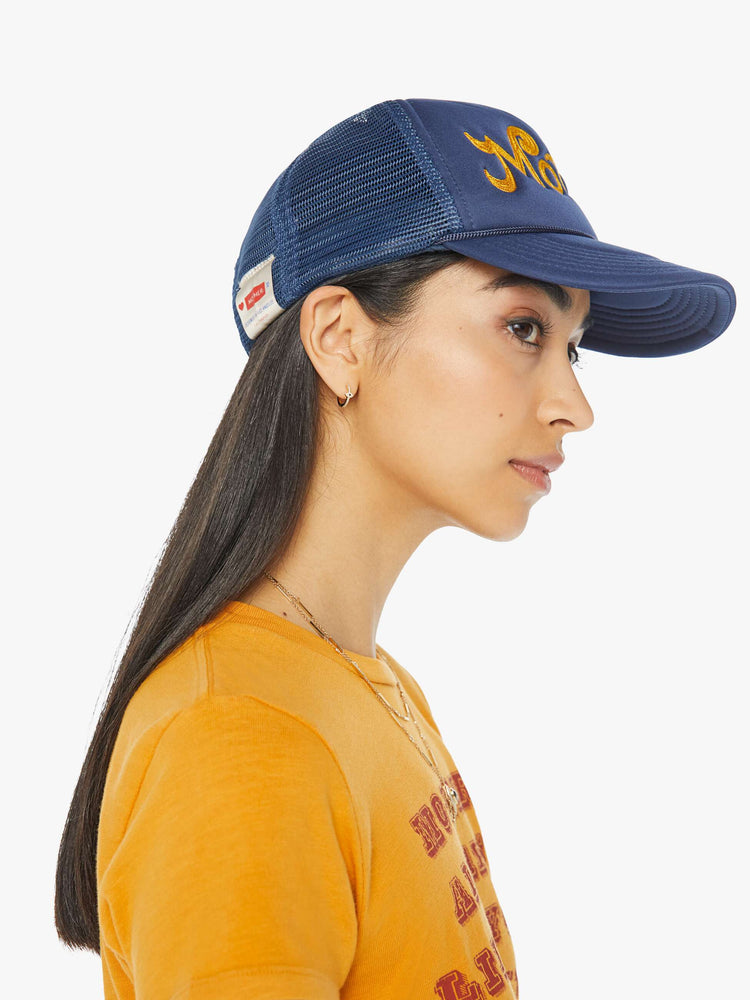 Side on model view of a vintage-inspired trucker hat designed in navy with MOTHER's name in golden yellow on the front.