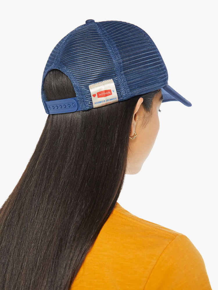 Back on model view of a vintage-inspired trucker hat designed in navy with MOTHER's name in golden yellow on the front.