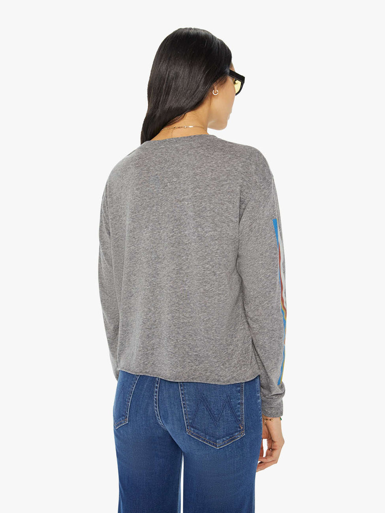 Back view of a woman in an oversized grey long-sleeve crewneck with MOTHER's name across the chest, and a slightly cropped cutoff hem. 