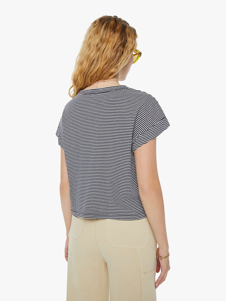 Back view of a woman in a nautical white and navy striped cropped crewneck tee with short rolled sleeves, a chest pocket and a boxy fit. 