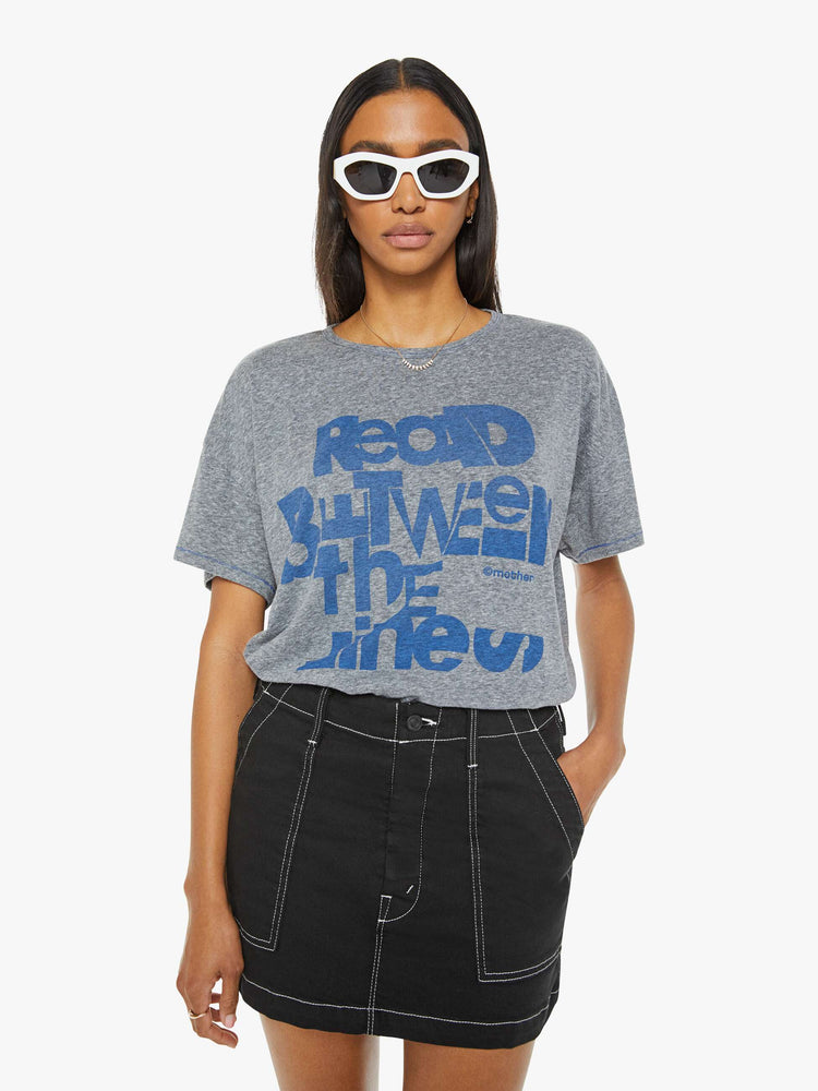 Front view of a woman in a heathered grey oversized tee with drop shoulders and loose boxy fit with blue text graphic.