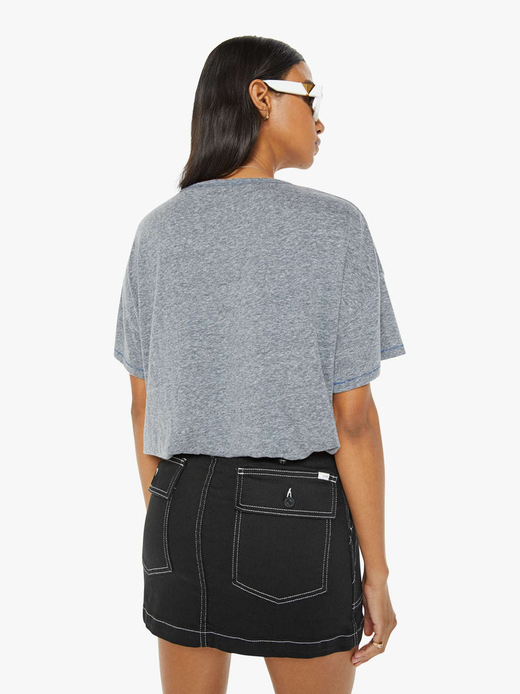 Back view of a woman in a heathered grey oversized tee with drop shoulders and loose boxy fit with blue text graphic.