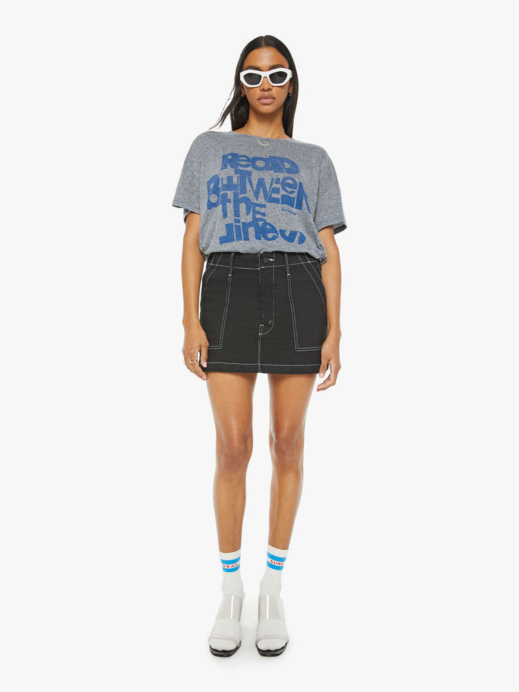 Full body view of a woman in a heathered grey oversized tee with drop shoulders and loose boxy fit with blue text graphic.