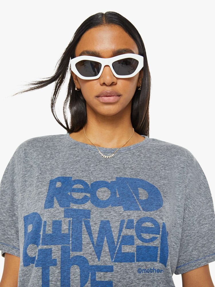 Close up view of a woman in a heathered grey oversized tee with drop shoulders and loose boxy fit with blue text graphic.