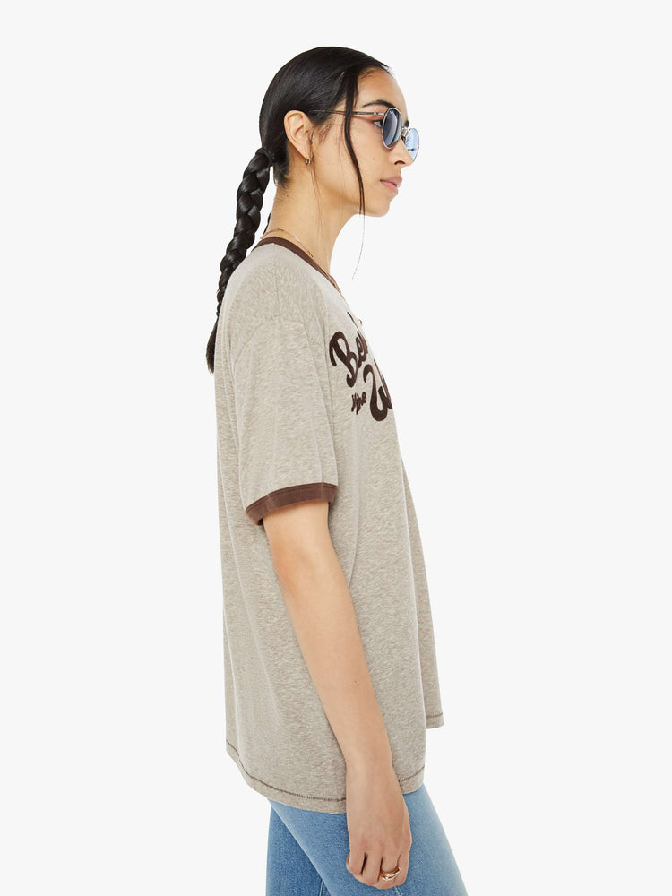 Side view of a woman marled tan oversized tee with drop shoulders and a loose fit with a red heart near the collar.